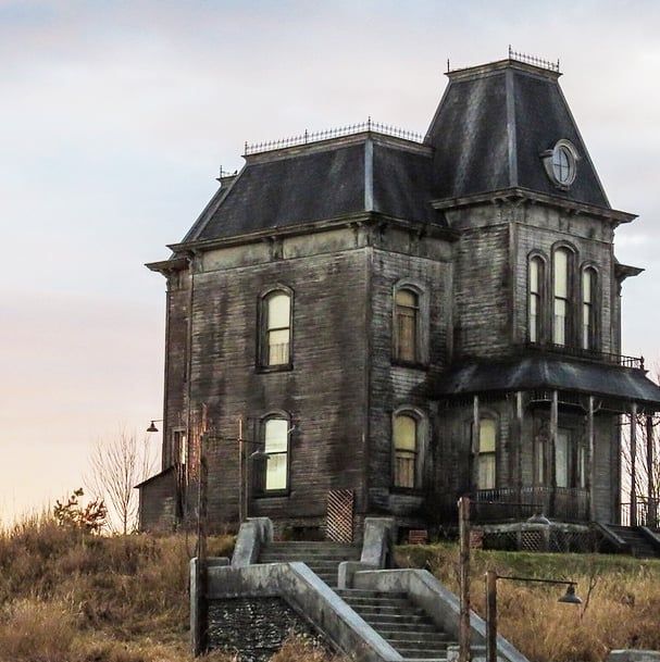 an old house sitting on top of a hill with stairs leading up to the roof