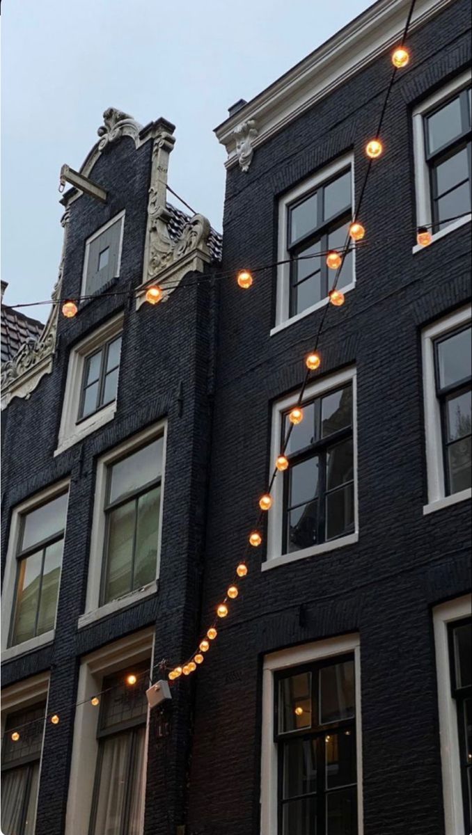 there are many lights strung on the side of this building in front of some windows