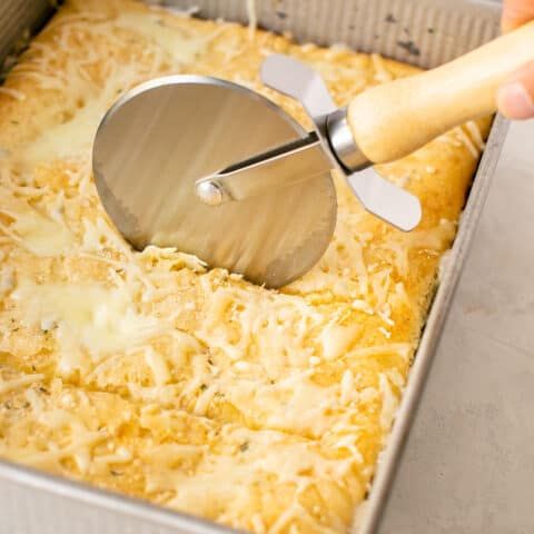 a person using a spatula to mix cheese into a casserole dish in a pan