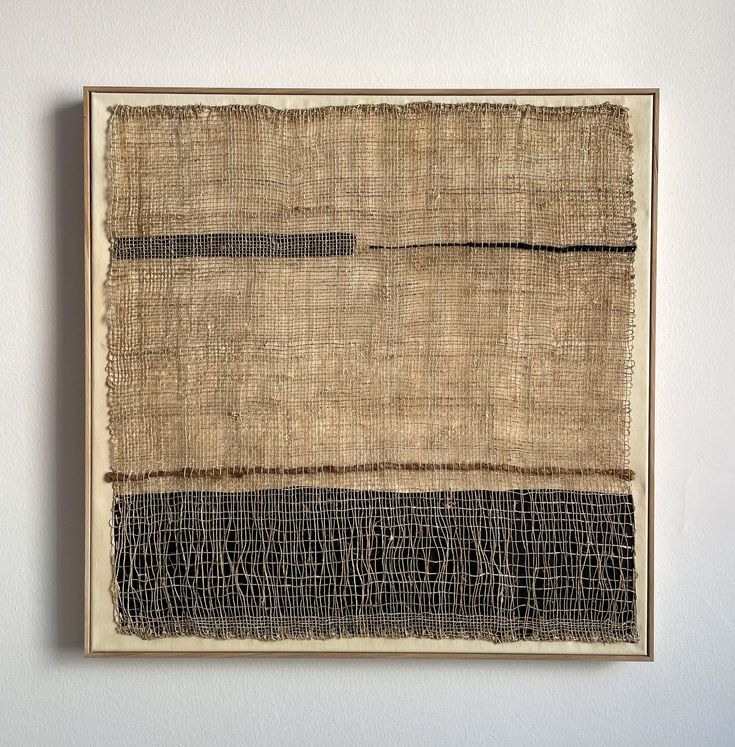 a piece of art hanging on the wall with burlap and black lines painted on it