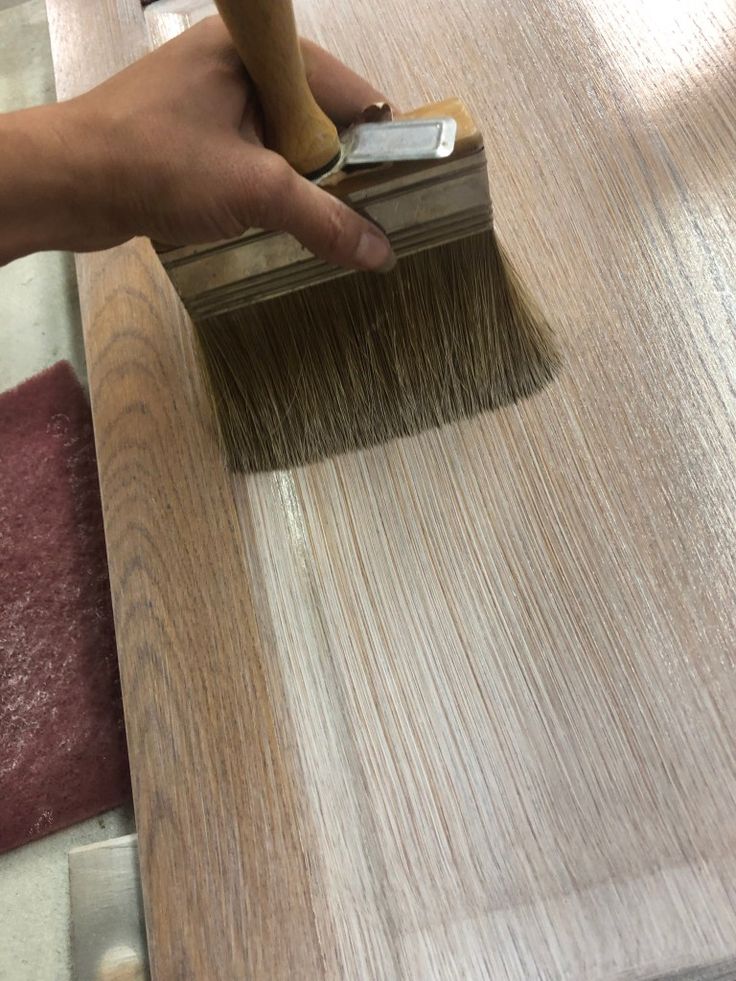 a person using a brush to paint wood