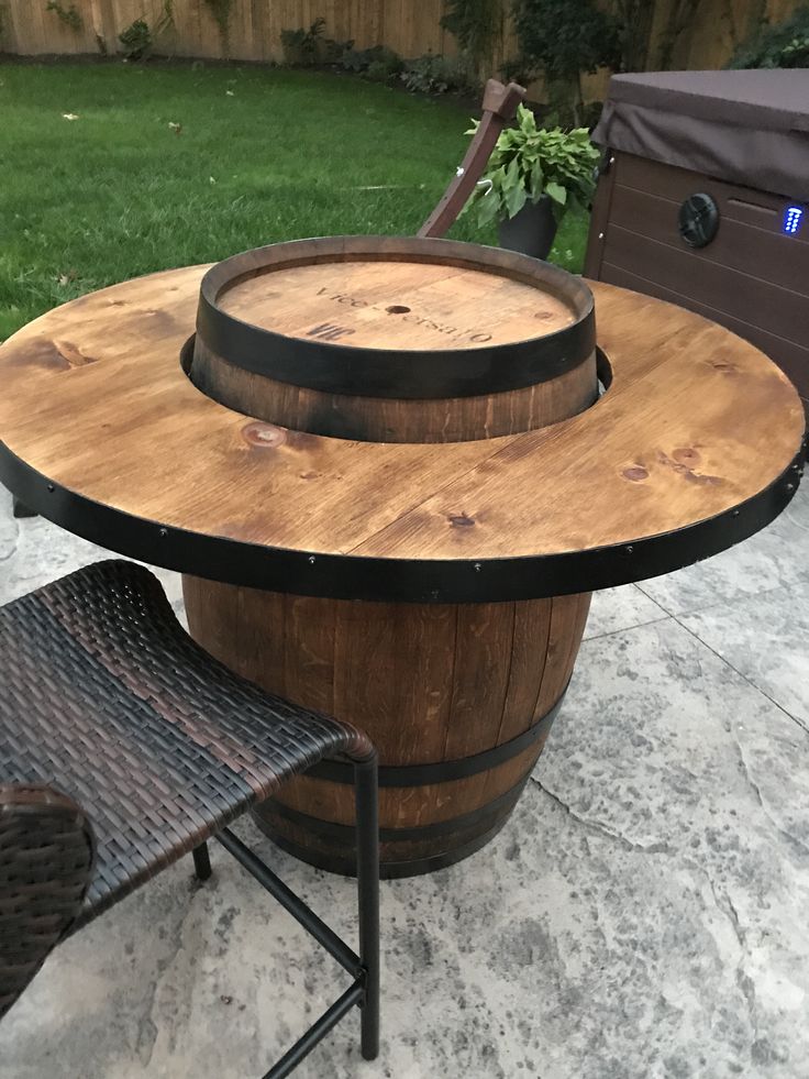 a wooden barrel table sitting on top of a patio next to a brown wicker chair