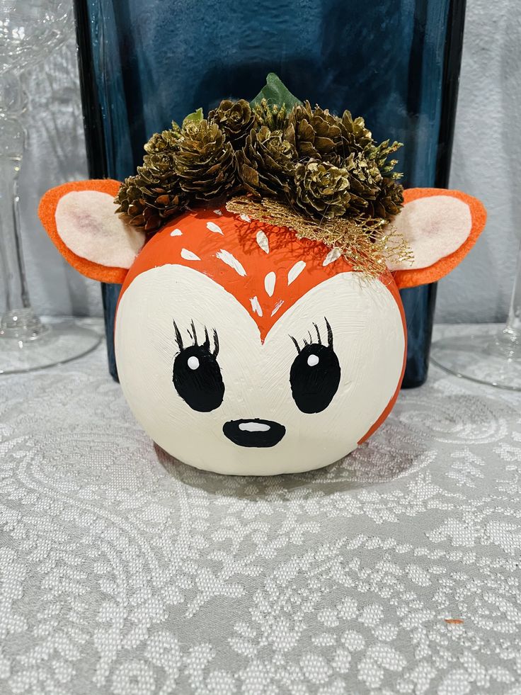 an orange and white pumpkin with a deer head on it's head is sitting on a table