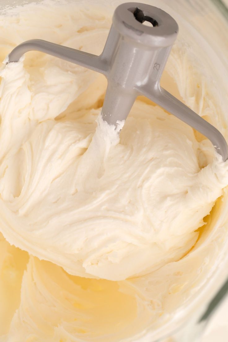 a mixer filled with white batter in a glass bowl