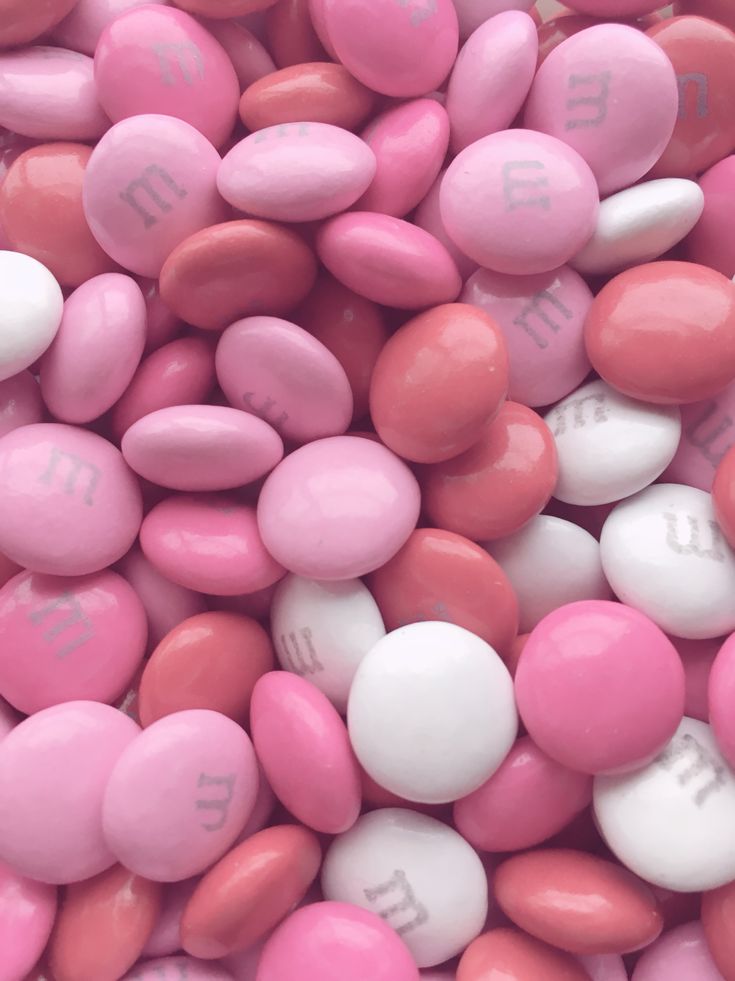 pink and white candy pebbles with the word m e n d s on them are shown in close up