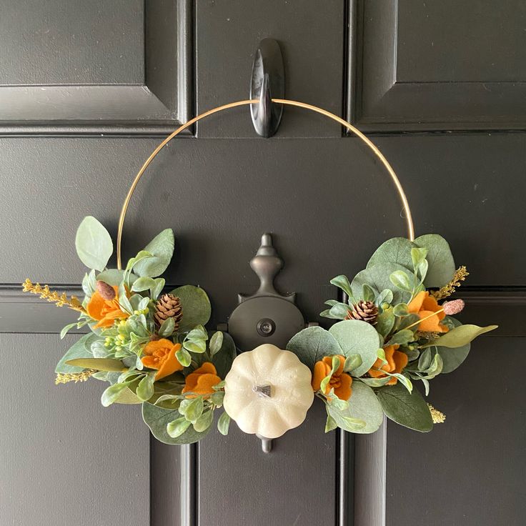 a wreath with flowers and leaves hanging on a door