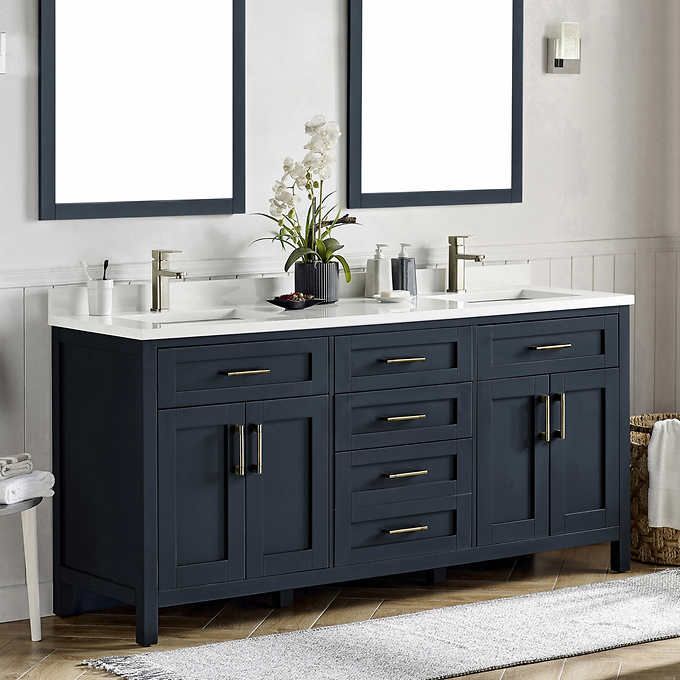 two mirrors are above the double sink vanity in this white and blue bathroom with wood flooring