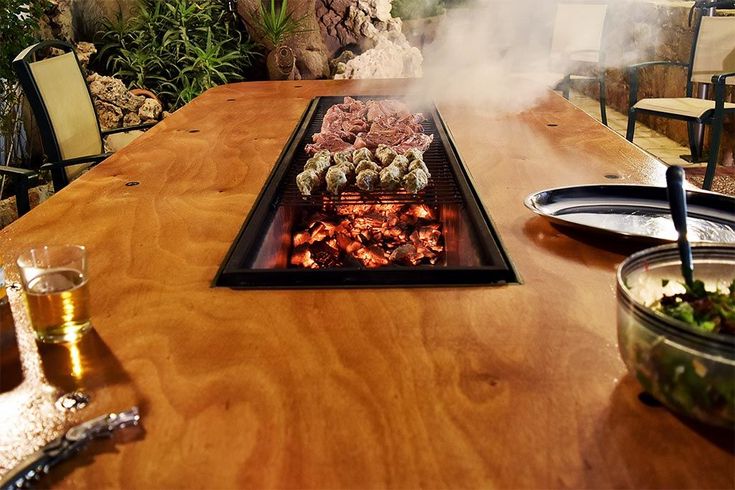 an outdoor bbq grill with food and drinks on the table in front of it