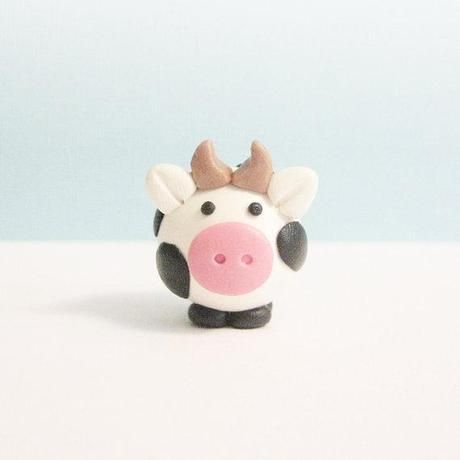 a small toy cow with horns on it's head sitting on a white surface