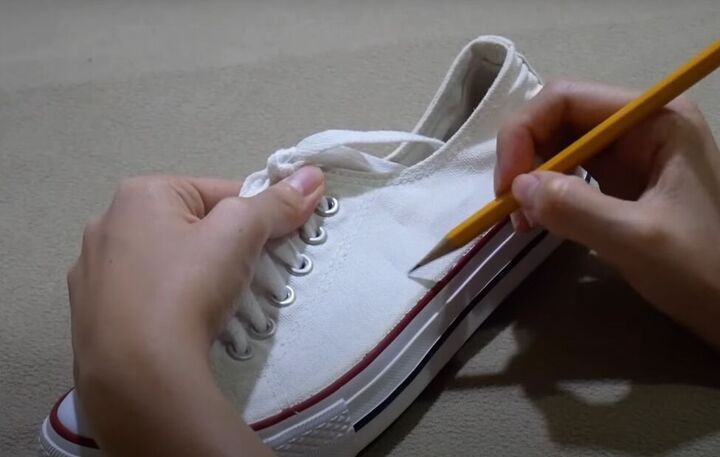 a person is holding a pencil and writing on a pair of white shoes