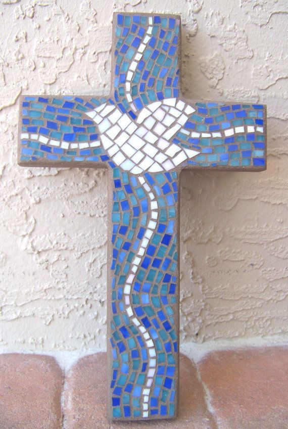 a blue and white mosaic cross sitting on top of a brick floor next to a wall