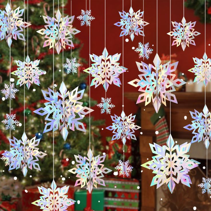 snowflakes hanging from strings in front of a christmas tree