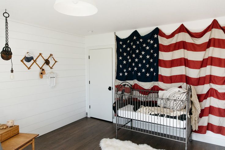 a baby crib with an american flag hanging on the wall