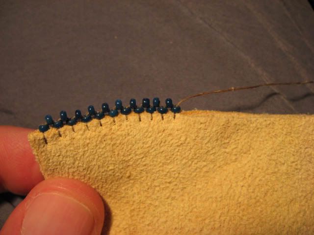 a hand holding a piece of yellow fabric with blue pins in the middle of it