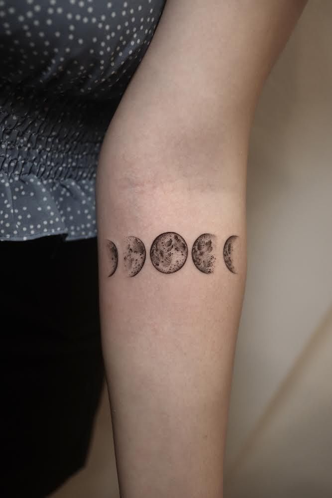 a woman's arm with three phases of the moon tattoo on it