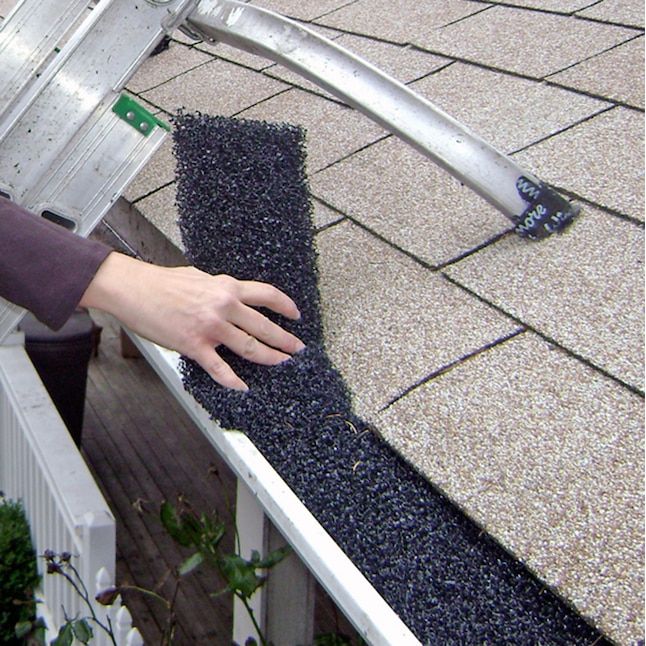 a person reaching down to grab something out of the gutter on top of a roof