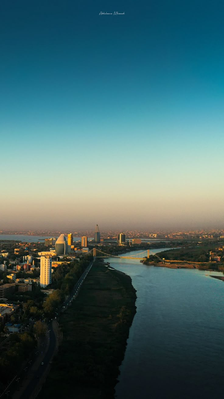 an aerial view of a river and city with tall buildings in the distance, taken from above