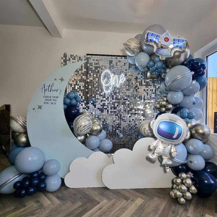 an astronaut balloon arch with silver and blue balloons in the shape of clouds, stars and planets