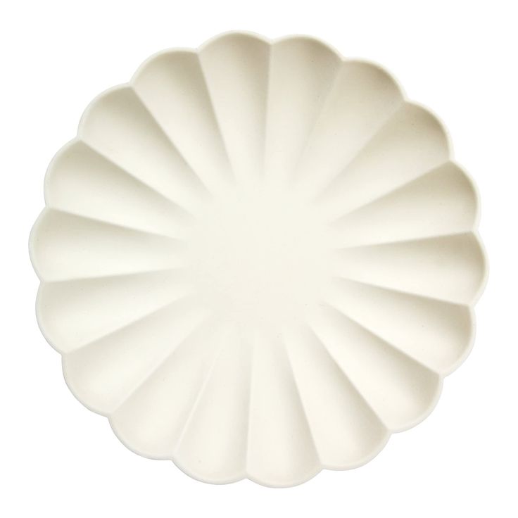 a large white plate with scalloped edges on a white background, viewed from above