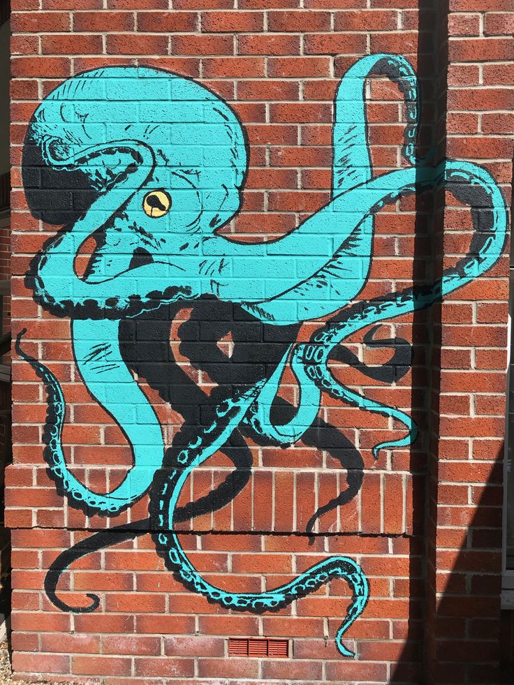 an octopus painted on the side of a brick building with blue paint and black outline