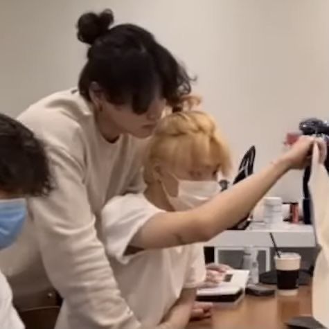 two women in masks are looking at something on the table while another woman holds her hand out