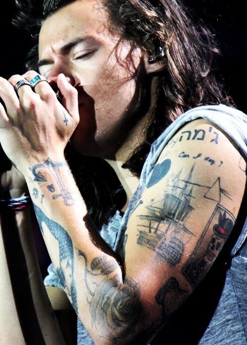 a man with long hair and tattoos on his arm is holding a microphone to his mouth