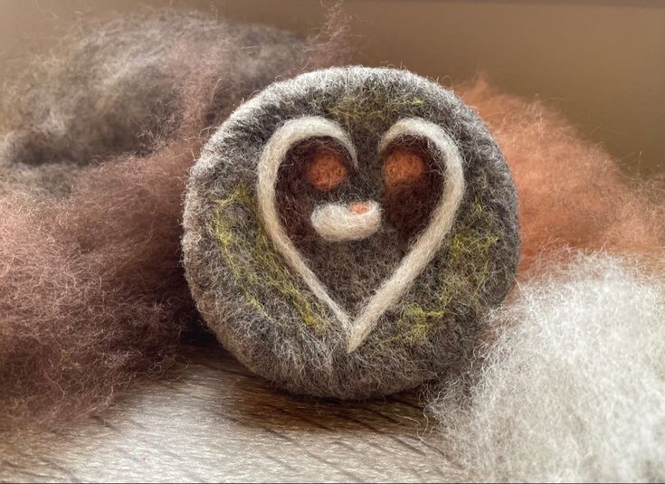 a wool ball with a heart shaped decoration on top of some brown and white fibers