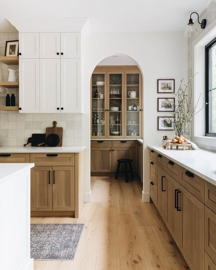 a large kitchen with wooden cabinets and white counter tops, along with an arched doorway leading to the dining room