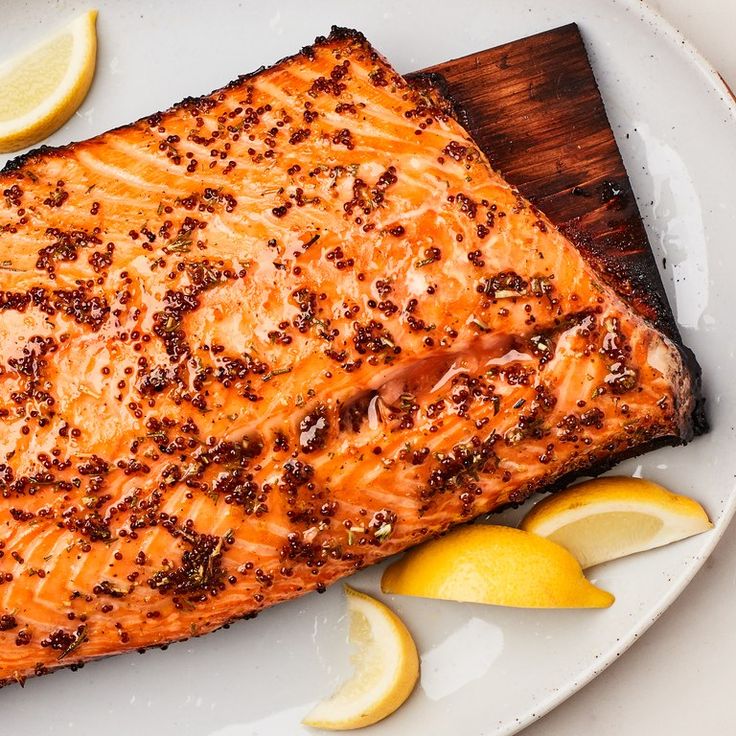 a piece of salmon on a plate with lemons