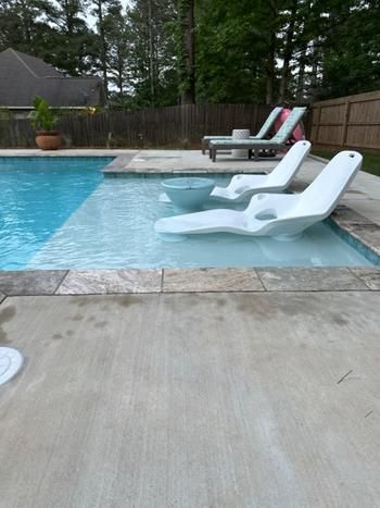 an empty swimming pool with lounge chairs next to it