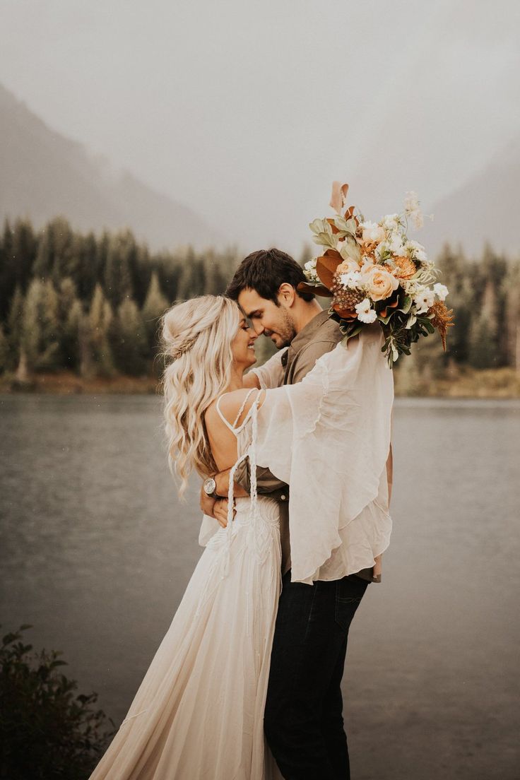 a man and woman standing next to each other in front of a lake