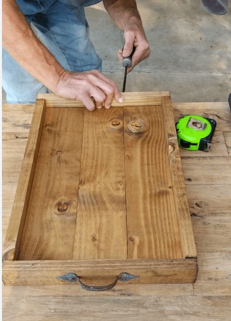 a man is working on a piece of wood with a drill and screwdriver