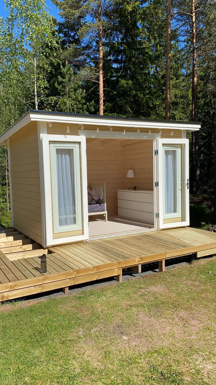 a small wooden cabin with sliding glass doors on the outside and decking in front