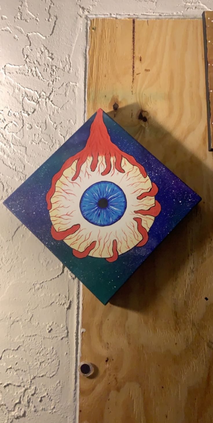 an eyeball painted on the side of a wooden wall with wood planks around it