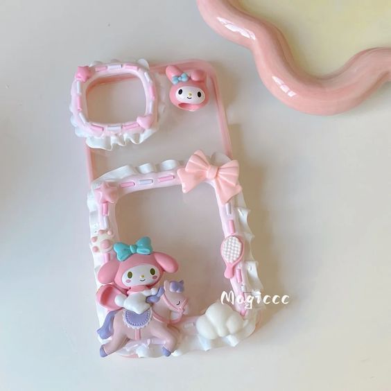 a pink phone case sitting next to a small toy bear and teddy bear figurine