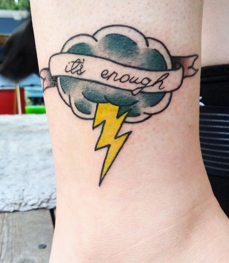 a woman's foot with a cloud and lightning tattoo on it