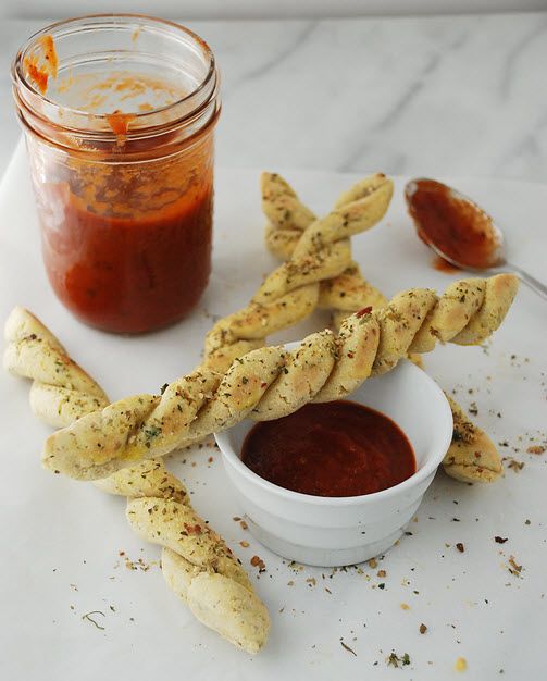 some breadsticks are next to a jar of ketchup