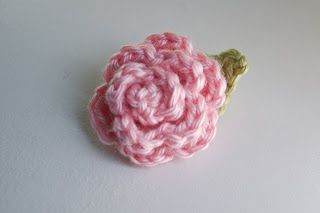 a crocheted pink flower on a white surface