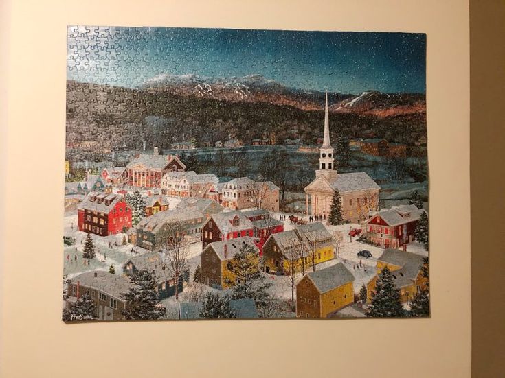 a jigsaw puzzle is hanging on the wall in front of a painting of a town