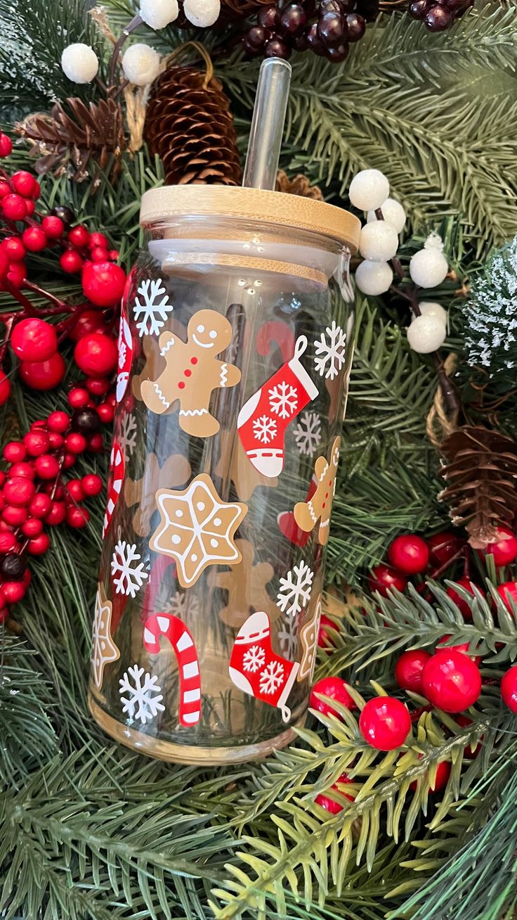 a cup with a straw in it sitting on top of a christmas tree next to berries and pine cones