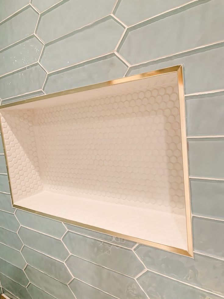 a white toilet sitting next to a blue tiled wall with gold trim on the edge