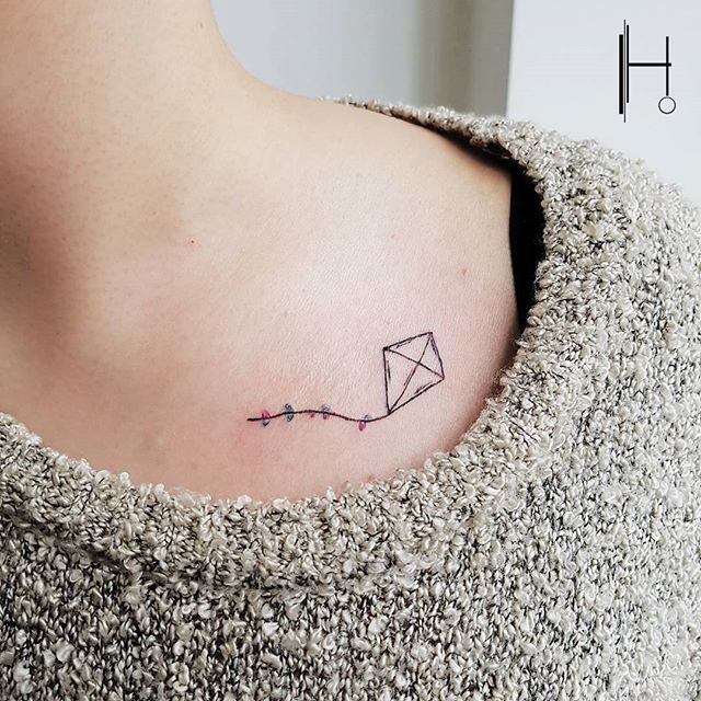 a woman with a small tattoo on her chest that has a kite flying in the sky