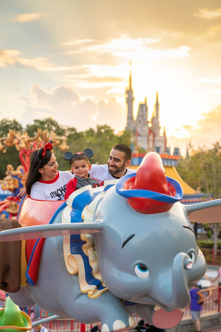 a man and woman ride an elephant at the amusement park with their child on it