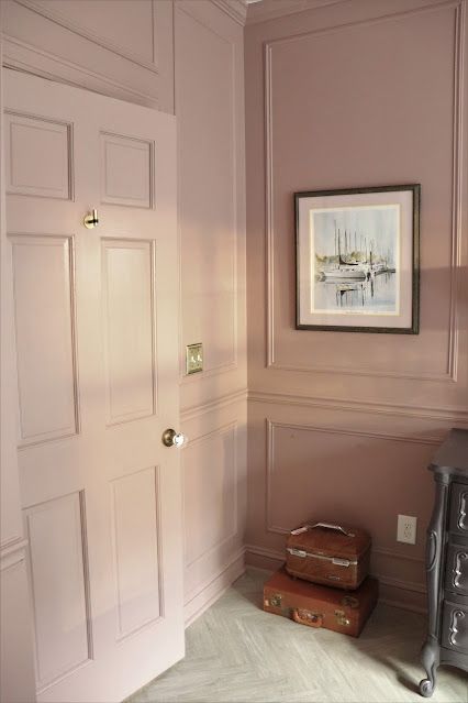 a room with pink walls and two suitcases on the floor in front of it