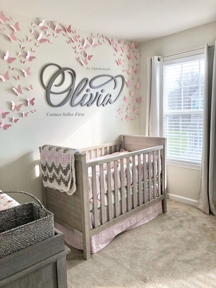 a baby's room decorated in pink and gray with butterflies on the wall above it