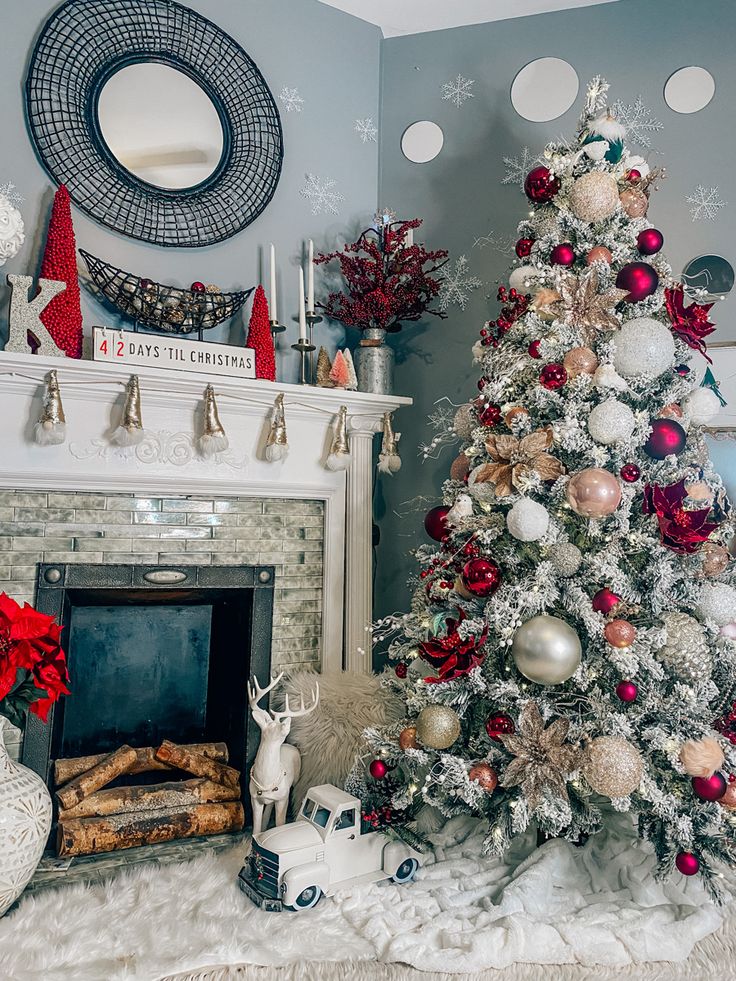 a decorated christmas tree sitting in front of a fire place next to a white fireplace