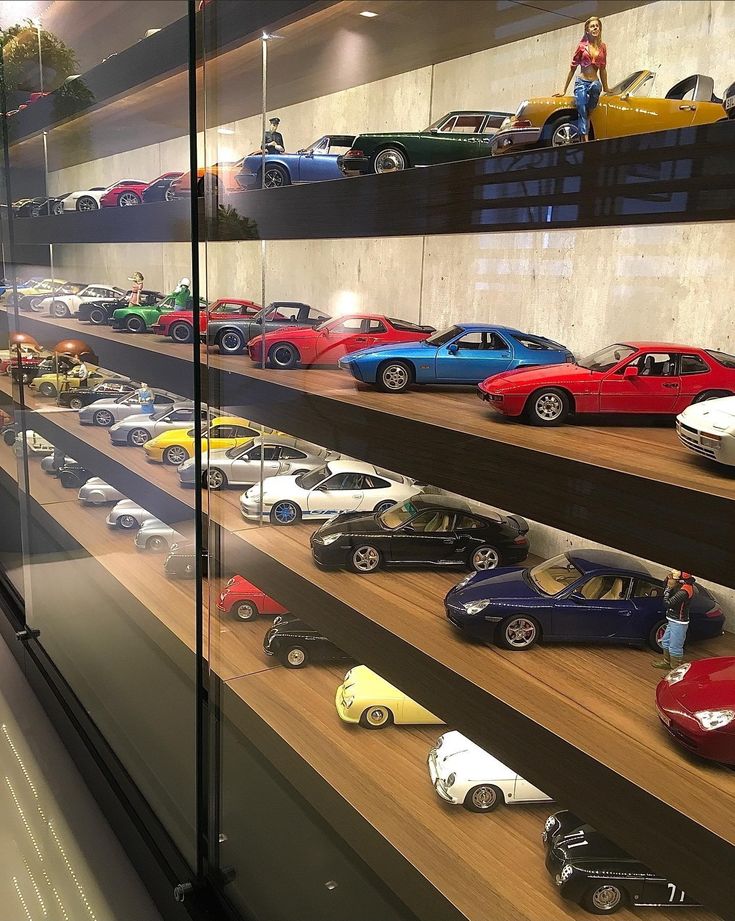 a display case filled with lots of different types of toy cars on top of wooden shelves