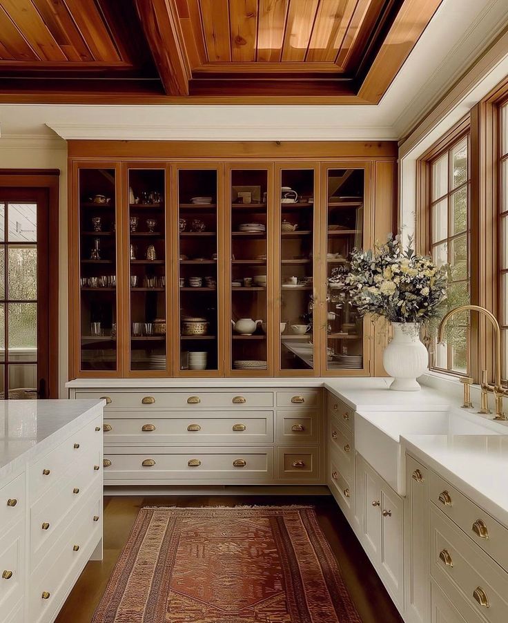 a kitchen with wooden ceiling and white cabinets, an area rug on the floor in front of it