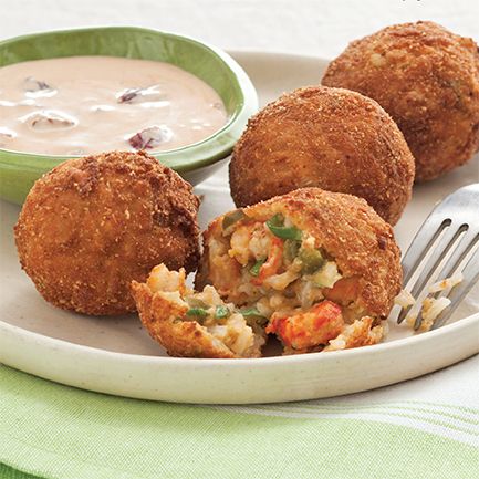 three fried food items on a plate with a fork and bowl of soup in the background