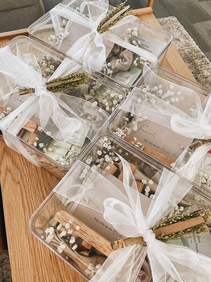 several clear plastic containers filled with flowers and pictures on a table top next to a wooden chair